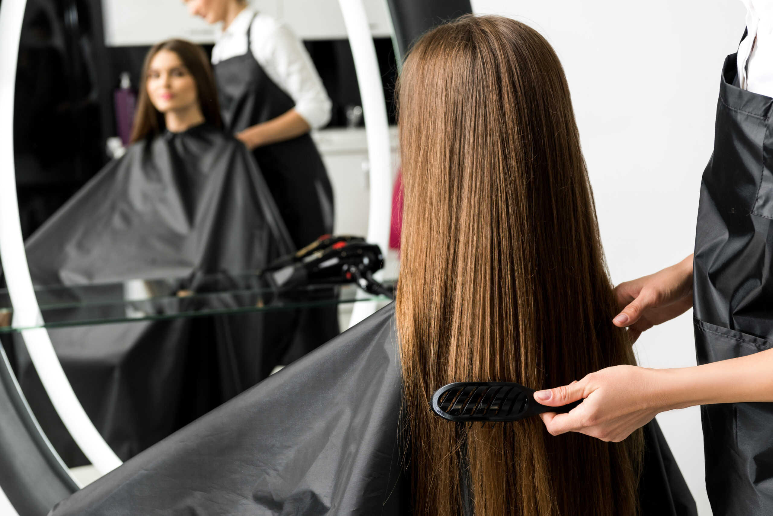 hairdresser brushing hair of woman in beauty salon hairdresser brushing hair of woman in beauty salon