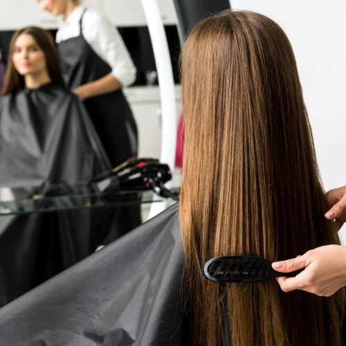 hairdresser brushing hair of woman in beauty salon